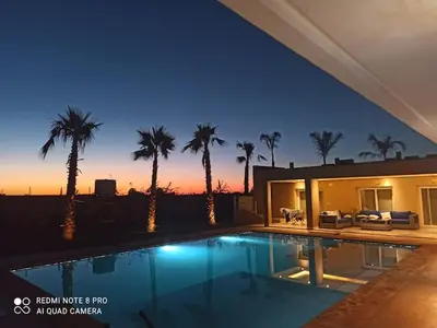 a villa with a swimming pool at night with palm trees at Bienvenu chez VillAtlas in Marrakech