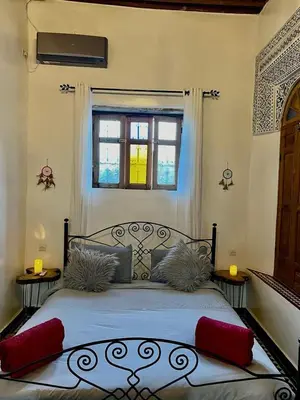 a bedroom with a bed with red pillows and a window at DAR Naima in Fès