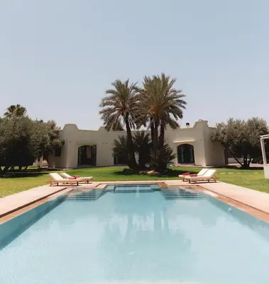 a swimming pool with two chairs and a house at Villa Daïs - Marrakech in Marrakech