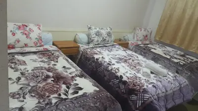 a bedroom with two beds with floral sheets and pillows at Hotel Opéra Azrou in Azrou