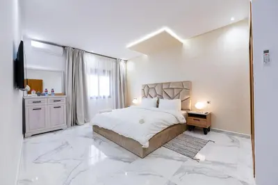 a white bedroom with a large bed and a mirror at Cozy Apartment in new town in Fès