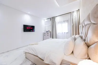 a white bedroom with a large bed and a window at Cozy Apartment in new town in Fès