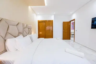 a white bedroom with a large bed with white pillows at Cozy Apartment in new town in Fès