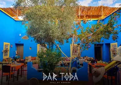 a blue building with tables and chairs in front of it at Dar Toda - Zagora guest house in Zagora