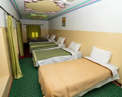 three beds in a room with green carpet at Gite Tamounte in Tabant