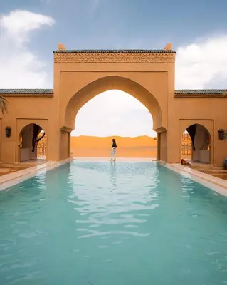 a person standing in a pool of water in the desert at Sahara pearl Hotel in Merzouga