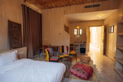 a bedroom with a bed and a table and a kitchen at Sahara pearl Hotel in Merzouga