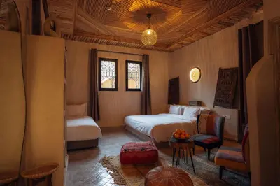a bedroom with a bed and a table and a chair at Sahara pearl Hotel in Merzouga