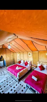 two beds in a room with a tent at Najma Luxury Camp in Merzouga