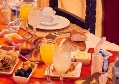 a table with plates of food and glasses of orange juice at Najma Luxury Camp in Merzouga