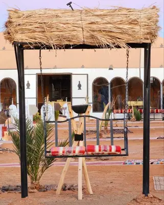 a bench with a straw roof on top of it at Najma Luxury Camp in Merzouga