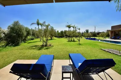 two blue lounge chairs on a patio next to a pool at Villa à 30 mn de Marrakech. in El Aouina