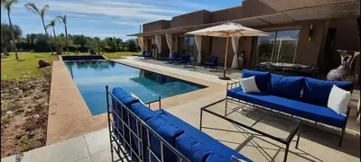 a house with a pool with blue furniture and an umbrella at Villa à 30 mn de Marrakech. in El Aouina