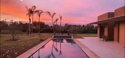 a swimming pool in front of a house with a sunset at Villa à 30 mn de Marrakech. in El Aouina