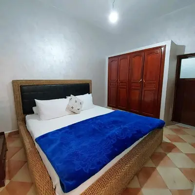 a bed with a blue blanket and a wooden cabinet at Cozy Appartement in Midelt in Midelt