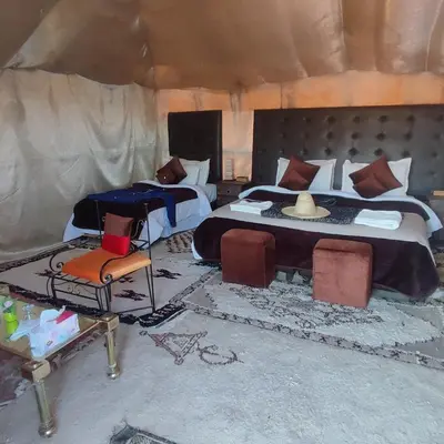 a bedroom with a bed and chairs in a tent at Overnight Luxury Camp in Merzouga