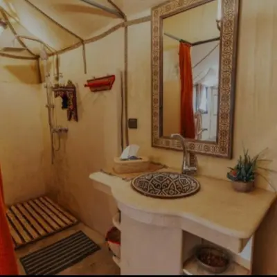 a bathroom with a sink and a shower with a mirror at Overnight Luxury Camp in Merzouga