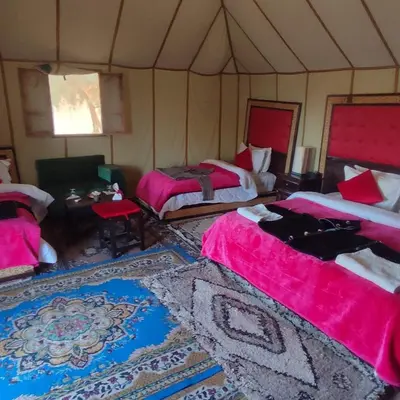a room with two beds and a table in a tent at Overnight Luxury Camp in Merzouga