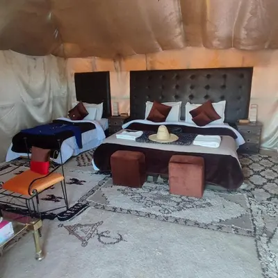 a bedroom with a large bed with a hat on it at Overnight Luxury Camp in Merzouga