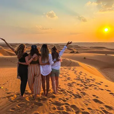 a group of women walking in the desert at sunset at Overnight Luxury Camp in Merzouga