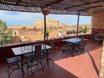 a patio with tables and chairs and a view of the desert at Appartement In Ksar Ait Ben Haddou in Aït Ben Haddou