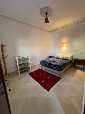 a bedroom with a bed and a red rug at Appartement In Ksar Ait Ben Haddou in Aït Ben Haddou