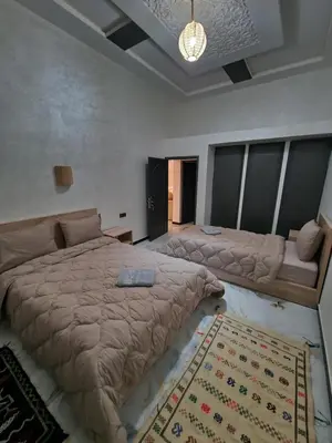 a bedroom with two beds and a rug at Appartement In Ksar Ait Ben Haddou in Aït Ben Haddou