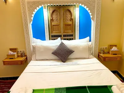 a bed with an ornate headboard in a room at Riad Noor Medina in Fès