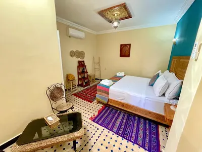 a bedroom with a bed and a table and a chair at Riad Noor Medina in Fès
