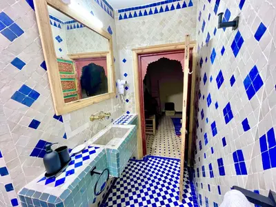 a blue and white bathroom with a sink and a mirror at Riad Noor Medina in Fès