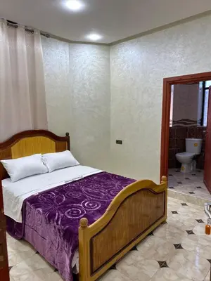 a bedroom with a bed with purple sheets and a toilet at HOTEL NOSTRESS in Khenifra