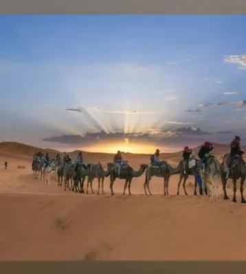 a group of people riding on camels in the desert at Dar Yaya & excursion - M'Hamid El Ghizlane in Mhamid
