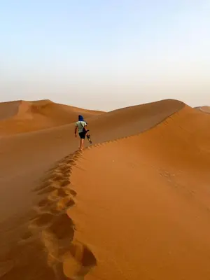 a man walking on a sand dune in the desert at Dar Yaya & excursion - M'Hamid El Ghizlane in Mhamid