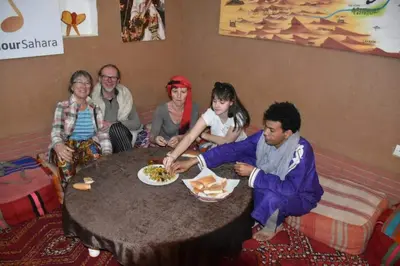 a group of people sitting around a table with a plate of food at Dar Yaya & excursion - M'Hamid El Ghizlane in Mhamid
