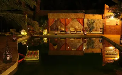 a swimming pool at night with a table and chairs at Dar Pienatcha in Zagora