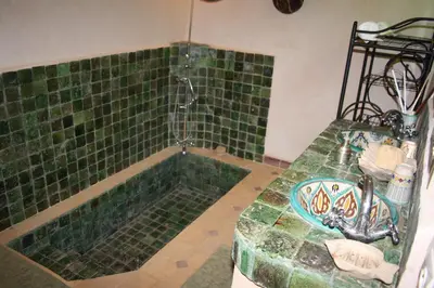 a bathroom with a green tiled tub with a shower at Dar Pienatcha in Zagora