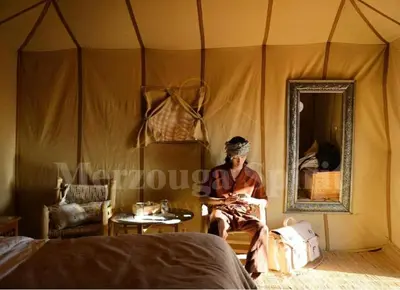 a man sitting in a room in a tent at Merzouga Spirit Luxury Camp in Merzouga