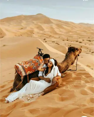 a man and a woman sitting on a camel in the desert at Merzouga Spirit Luxury Camp in Merzouga