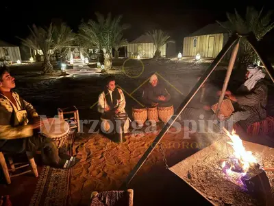 a group of people sitting around a camp fire at Merzouga Spirit Luxury Camp in Merzouga