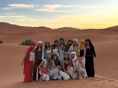 a group of women posing for a picture in the desert at Gorgeous Luxury Camp in Merzouga
