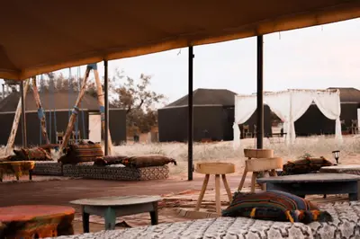 a tent with tables and chairs in a field at Gorgeous Luxury Camp in Merzouga