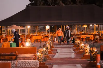a group of people walking down a walkway with lights at Gorgeous Luxury Camp in Merzouga