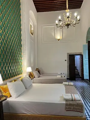 a bedroom with two beds and a chandelier at Palais Chahd Luxury in Fès