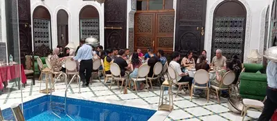 a group of people sitting in chairs around a pool at Palais Chahd Luxury in Fès