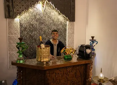 a man is standing behind a table with bottles at Palais Chahd Luxury in Fès