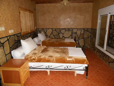 a bedroom with two beds and a table at La Petite Gorge, Hôtel & Restaurant Todra Gorge in Tinerhir