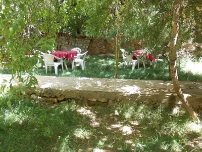 a group of tables and chairs under trees at La Petite Gorge, Hôtel & Restaurant Todra Gorge in Tinerhir