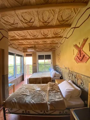 a bedroom with two beds and a wooden ceiling at La Petite Gorge, Hôtel & Restaurant Todra Gorge in Tinerhir