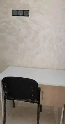 a black chair sitting under a white wall at Bel appartement calme est bien équipé in Meknès