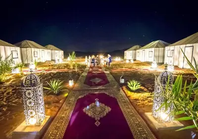 a courtyard at night with lights and tents at Merzouga desert Luxury Camp in Merzouga
